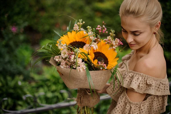 Schöner heller Strauß Sonnenblumen in den Händen einer jungen Frau — Stockfoto