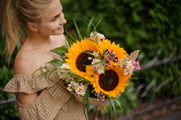 Grande bouquet luminoso di girasoli nelle mani di giovane donna — Foto Stock