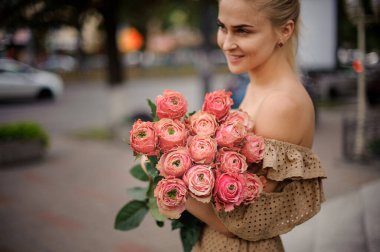 Gülümseyen genç bir kadının elinde çiçek buketindeki gül goncalarının mükemmel manzarası.