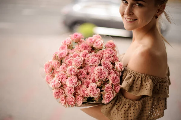Bel mazzo di piccole rose rosa fresche nelle mani di giovane donna sorridente — Foto Stock