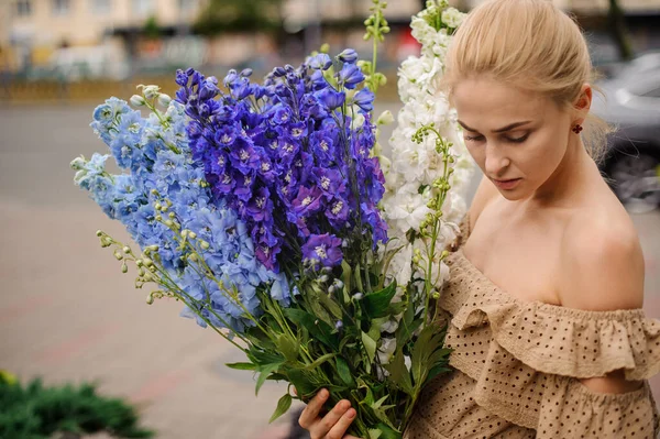 Ung attraktiv blond kvinna med massor av flerfärgade delfinblommor — Stockfoto