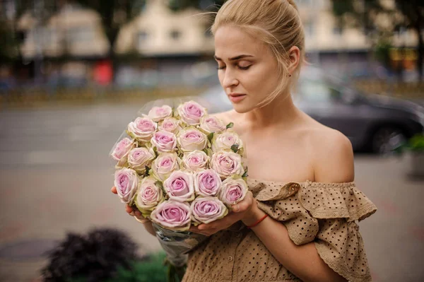 Jovem mulher loira bonito com belo buquê de rosas frescas em suas mãos — Fotografia de Stock