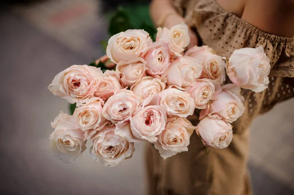 Close-up view on beautiful bouquet of fresh cream roses in hands of woman — Stockfoto