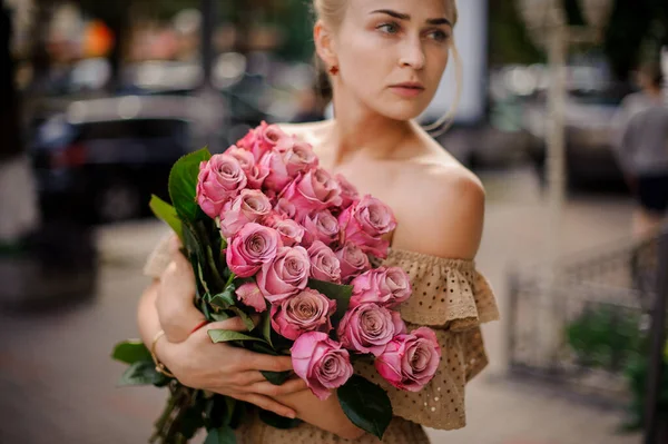 Young blonde woman tightly holding bouquet of beautiful roses in her hands — Photo