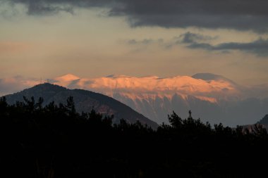Gökyüzü bulutları üzerinde renkli ve canlı güneş ışığıyla muhteşem dağ manzarası, doğa.