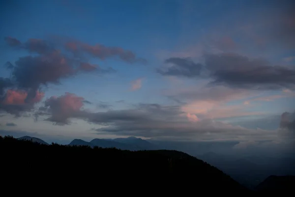 Céu glamouroso com nuvens vivas. Silhuetas escuras de montanhas e árvores ao amanhecer. — Fotografia de Stock