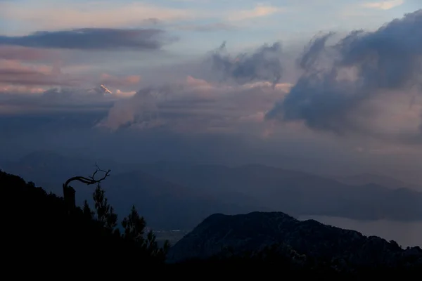 Majestueuze lucht met levendige wolken. Donkere silhouetten van bergen en bomen bij dageraad. — Stockfoto