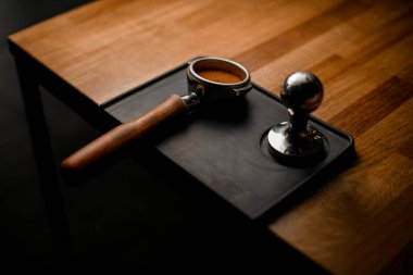 Doldurulmuş kahve ve öfkeyle portafilter manzarası Tahta masadaki siyah ayakta duruyor