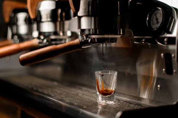 professional coffee machine automatically prepares and pours coffee drink into transparent glass