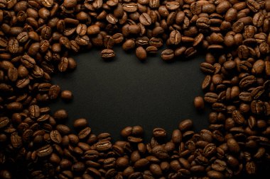 Siyah yüzeyde kahverengi kahve çekirdekleri kompozisyonu. Arkaplan olarak kullanılabilir.