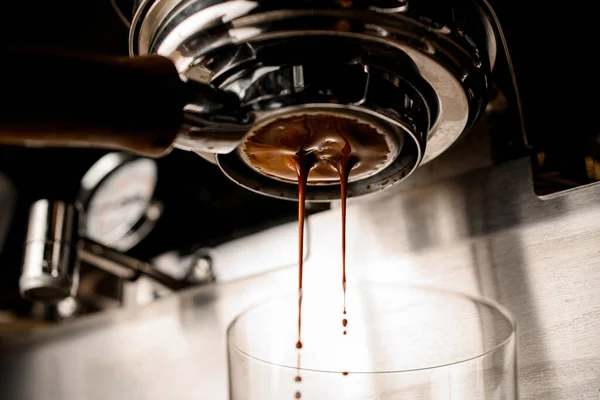 Vista inferior en portafilter de la máquina de café de la que la bebida fluye en el vidrio —  Fotos de Stock