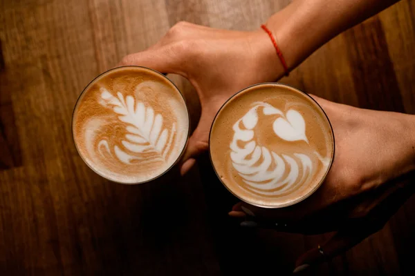 Kadın ellerinde latte sanatı olan bir bardak kahvenin üst görüntüsü. — Stok fotoğraf