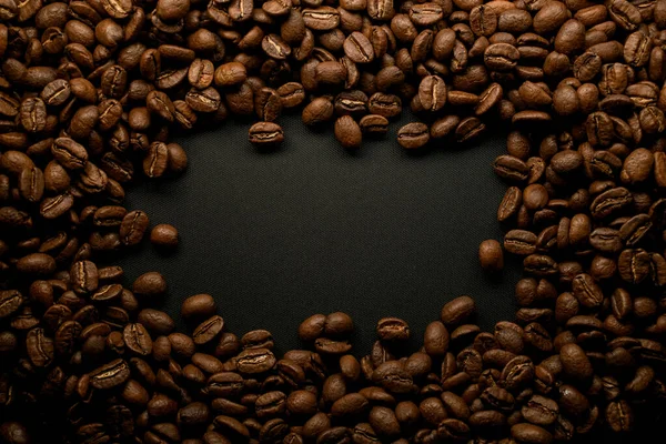 Composizione di chicchi di caffè torrefatto marrone su superficie nera. Può essere utilizzato come sfondo. — Foto Stock