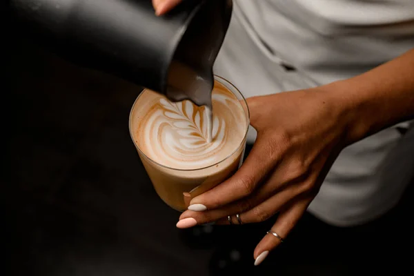 Gros plan de femme barista dessin doucement motif verser du lait dans le verre avec latte — Photo