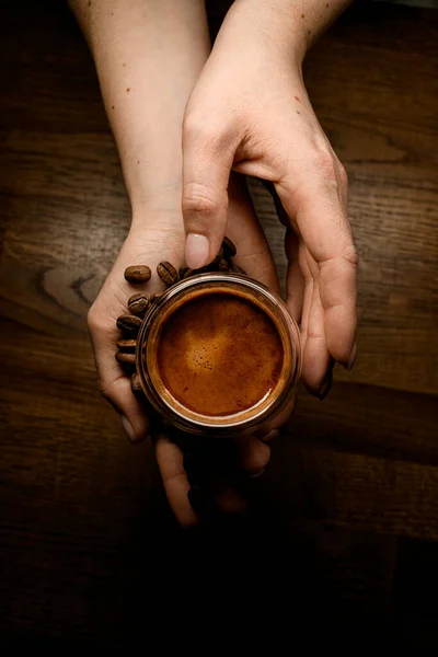 焙煎されたコーヒー豆と木製の表面上のコーヒーカップを保持する手で美しい景色 — ストック写真