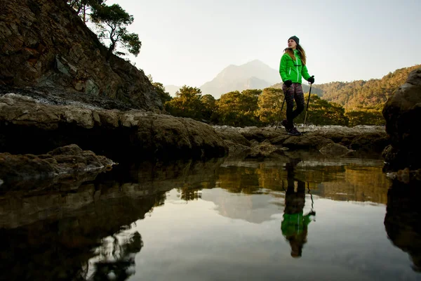 Charming view of water of mountain lake and young woman tourist standing near it — 스톡 사진