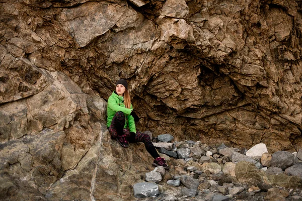 Молода спортивна жінка відпочиває на великому камені на тлі скелі — стокове фото