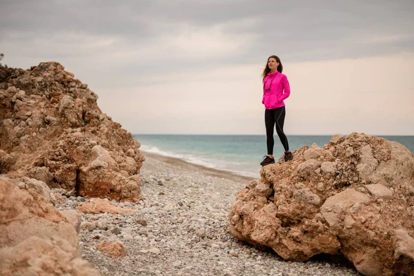 ผู้หญิงสาวที่น่าสนใจบนหินใหญ่บนพื้นหลังของชายฝั่งทะเล — ภาพถ่ายสต็อก