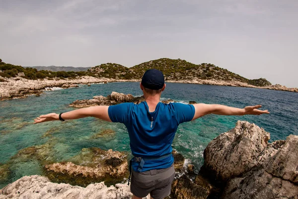 Bakre vy av turist kille sprider sina armar brett åt sidorna på havsutsikt bakgrund. — Stockfoto