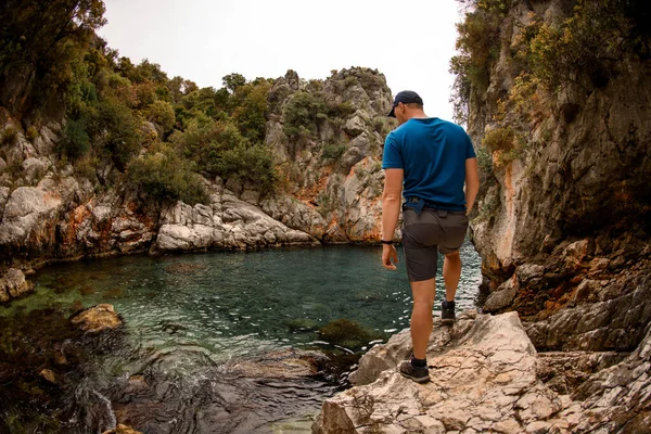 Вид ззаду чоловіка, що стоїть на камені біля води скелями — стокове фото