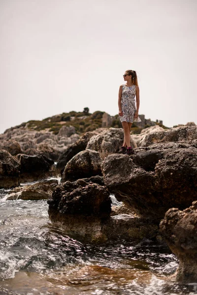 Vacker ung kvinna står på stor sten av havet kusten — Stockfoto