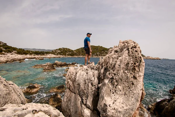 Man står på stor sten på stranden mot bakgrund av landskapet — Stockfoto