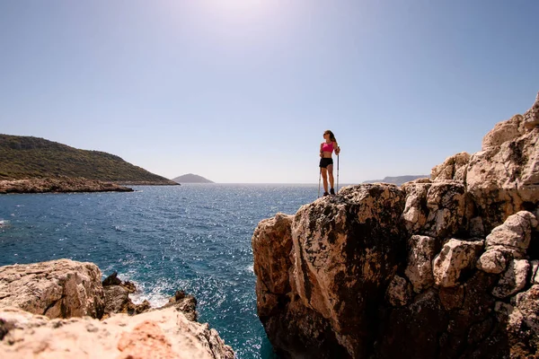 Uitzicht op vrouw staan op hoge rotsachtige klif tegen achtergrond van zeegezicht — Stockfoto