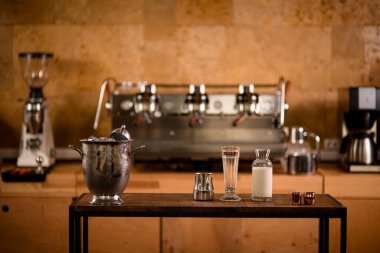 Kahve ve kokteyl yapmak için mutfak malzemeleriyle dolu bir masanın önü.