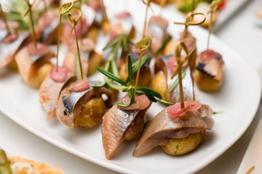 Sirkede soğanla servis edilen ve biberiyeyle süslenmiş balık parçalarının seçici odağı.