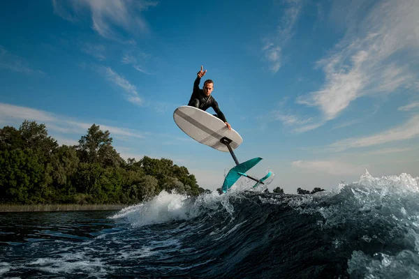 Junger Sportler springt mit Foilboard gekonnt auf der Welle — Stockfoto