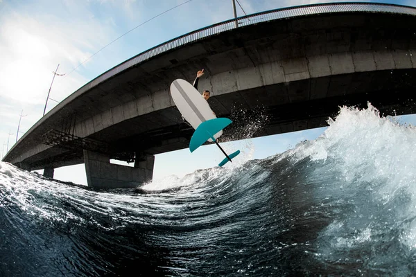 Sorprendente vista del tablero de hidroplanos y el hombre saltando sobre él por encima de la ola —  Fotos de Stock