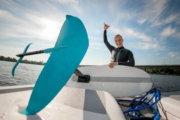 Foilboard e l'uomo in muta tenerlo e mostrando gesto della mano — Foto Stock