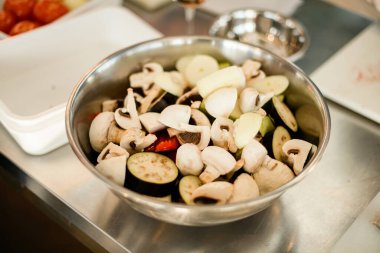 Kesilmiş şampiyonların ve patlıcanların çelik kasede seçilmiş odağı..