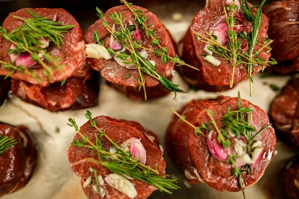 Close-up van groene rozemarijn takjes op stukken rauwe vlees steaks — Stockfoto