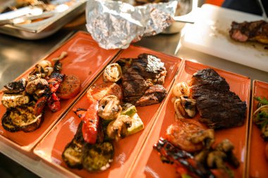 Fırında sebzeli tabaklar ve kızarmış et.