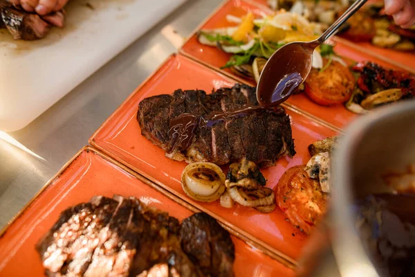 Close-up van stuk vlees op bord dat chef-kok schenkt met saus — Stockfoto