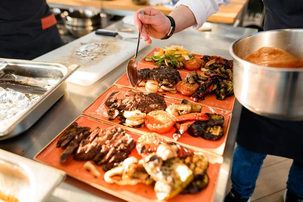 Вид на тарелки с блюдом, которое шеф-повар поливает соусом — стоковое фото