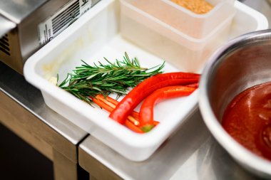 Taze biberiye filizi ve beyaz kutuda parlak kırmızı acı biber..