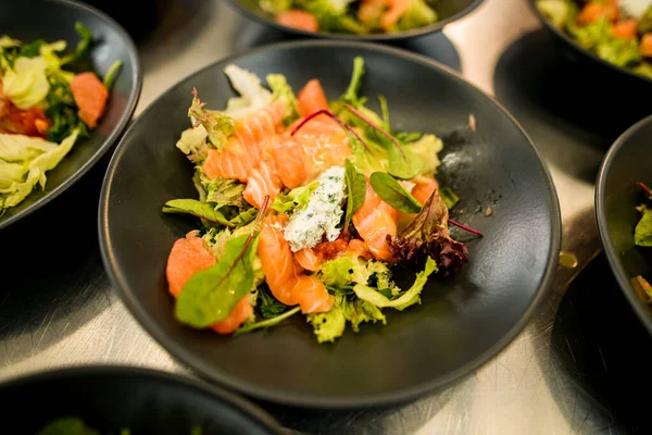 Primer plano del tazón negro de ensalada de salmón saludable sabrosa con rúcula y otras verduras — Foto de Stock