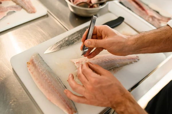 Manos de un hombre chef precisa limpia filetes de pescado de huesos. — Foto de Stock
