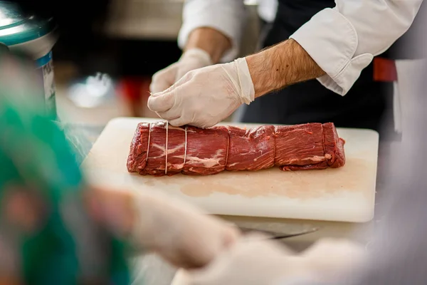 肉やシェフの手のクローズアップビューは、肉屋とそれを結ぶツイン — ストック写真