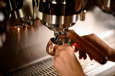 Kahve makinesinden bardaklara dökülen taze demlenmiş espresso yakın plan görüntüsü.