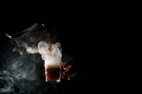 Женщины в темноте наливают горячий кофе из кофейника в прозрачную чашку — стоковое фото