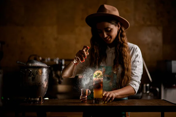 Jovem mulher sorridente bartender habilmente espirra em vidro com cocktail de café laranja frio — Fotografia de Stock