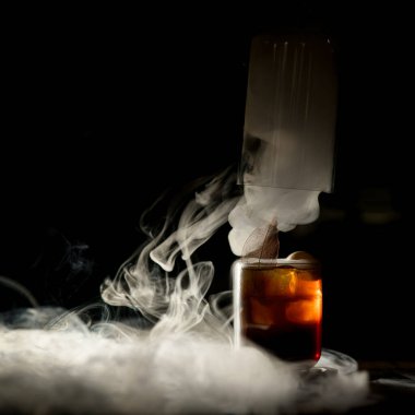 Bir bardak soğuk negroni içeceği yakın plan. Koyu buzlu bir barda.