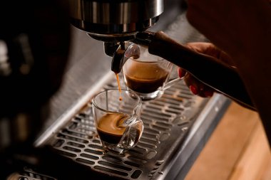 Bir espresso makinesinden fincana akan sıcak kahve akıntısına yakın çekim