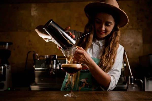 Mujer bonita camarera vertiendo cóctel de coctelera a través del tamiz a cristal —  Fotos de Stock