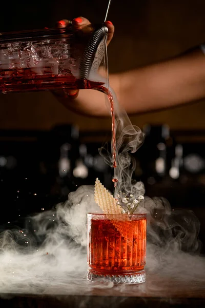 Doorzichtig glas met koude cocktail versierd met bloem waarin een drankje wordt gegoten — Stockfoto