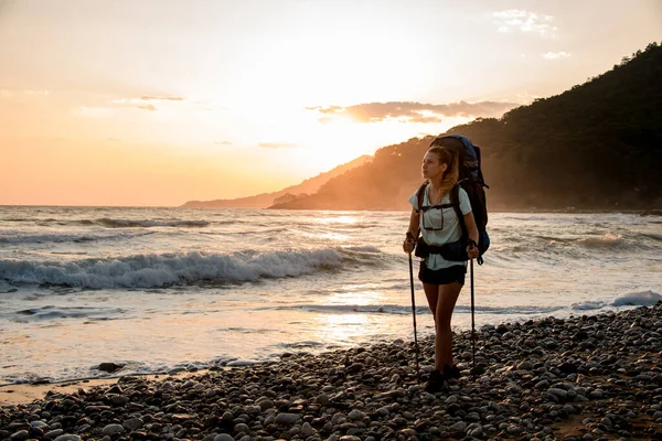Чарівна жінка турист на березі моря на тлі гір і заходу сонця — стокове фото