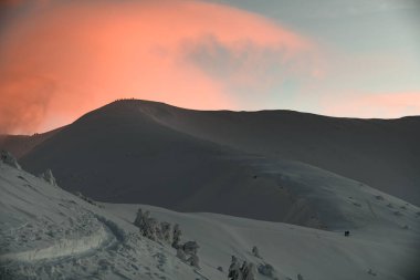 Üzerinde turist grupları olan karlı dağ zirvesi manzarası